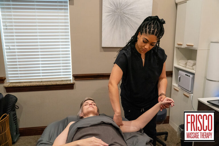 A massage therapist gently stretches a client's arm in a treatment room at Frisco Massage Therapy, offering relief for issues like surgical scar pain.