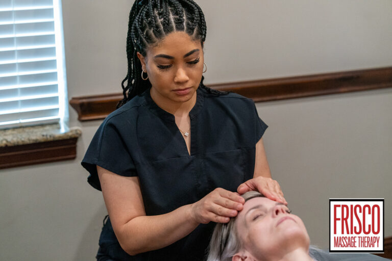 A massage therapist in black attire performs a facial massage on a client lying down inside a room, showcasing expertise in manual lymphatic drainage therapy near me. The logo "Frisco Massage Therapy" appears in the bottom right corner.