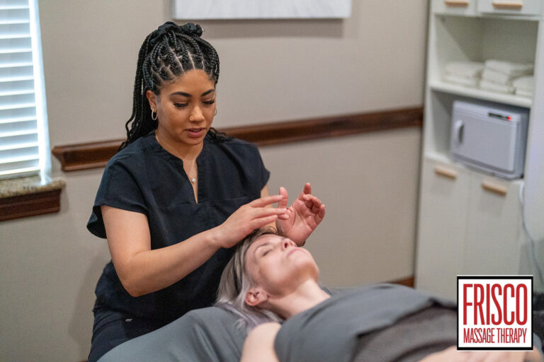 A massage therapist performs a manual lymphatic drainage facial massage on a client lying on a table in a spa room. The Frisco Massage Therapy logo is visible in the corner, highlighting the benefits of this relaxing treatment.