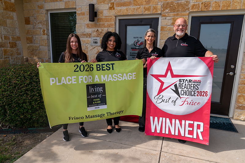 Four people stand outside a building holding banners that read “2026 Best Place for a Massage” and “Readers’ Choice Winner Best of Frisco 2026.”.