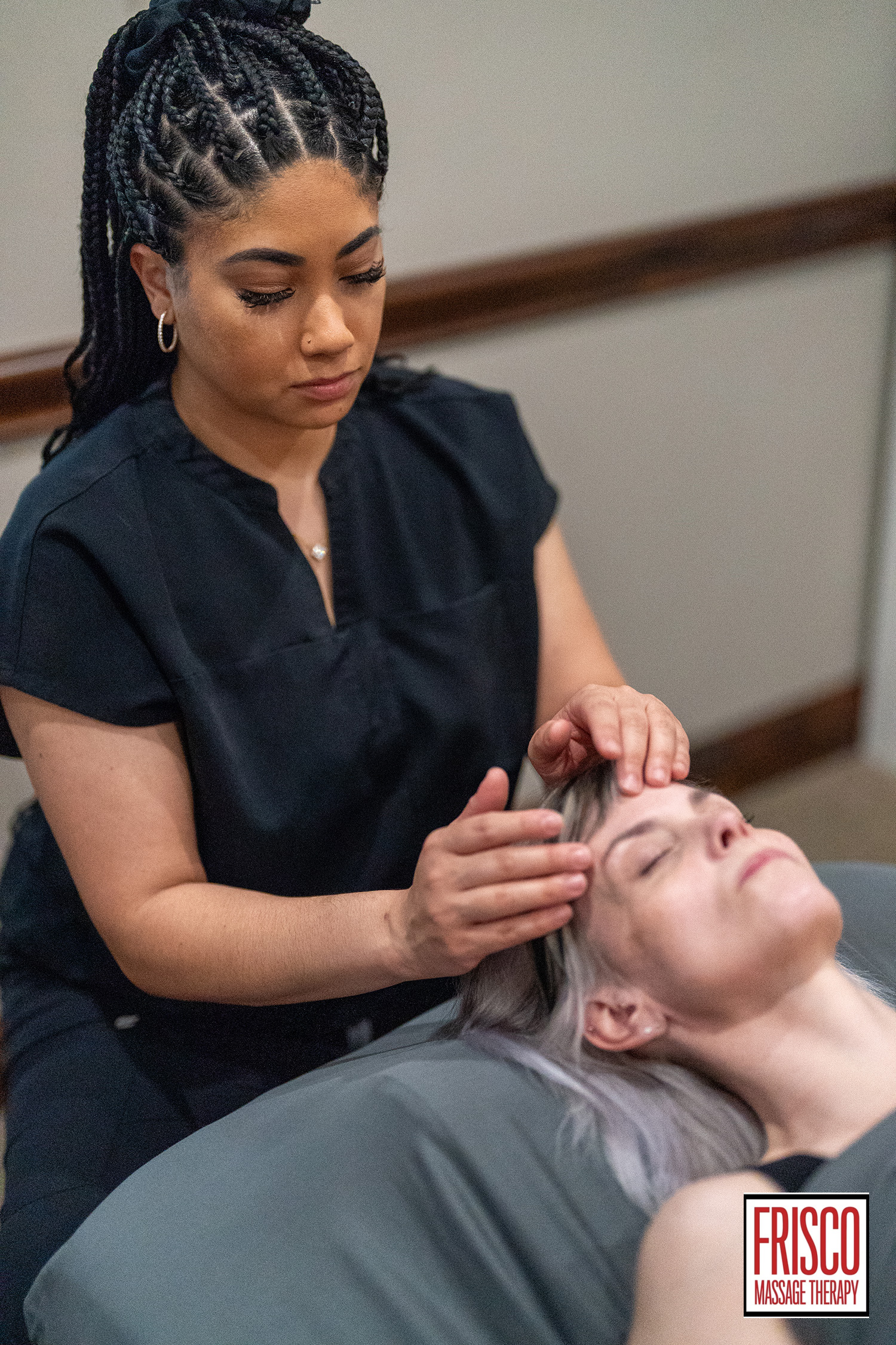 A massage therapist gives a head massage to a client lying on a table, focusing on techniques that can help with chronic pain. The Frisco Massage Therapy logo is visible in the bottom right corner.