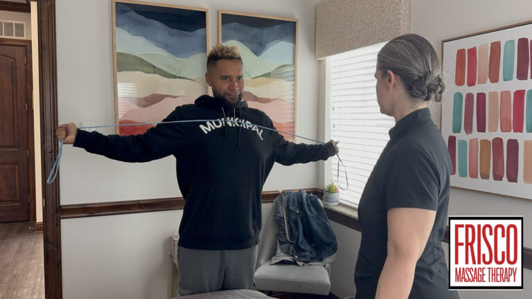 A person in a black hoodie stretches a resistance band in a therapy room while another person observes, highlighting how therapeutic massage aids in post-surgery recovery. A Frisco Massage Therapy logo is in the lower right corner.