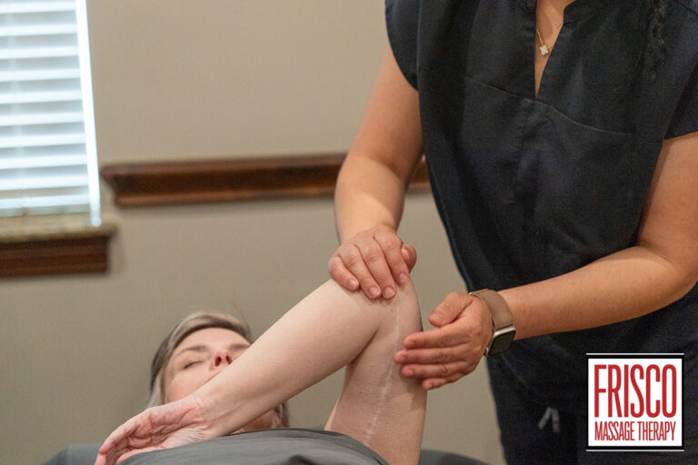A massage therapist stretches a client’s arm on a massage table at Frisco Massage Therapy, demonstrating how therapeutic massage helps scar tissue by increasing flexibility and promoting healing. The client’s eyes are closed, and the therapist is wearing a dark uniform.