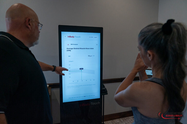 A person points to an InBody composition analysis screen displaying skeletal muscle mass results to a woman.
