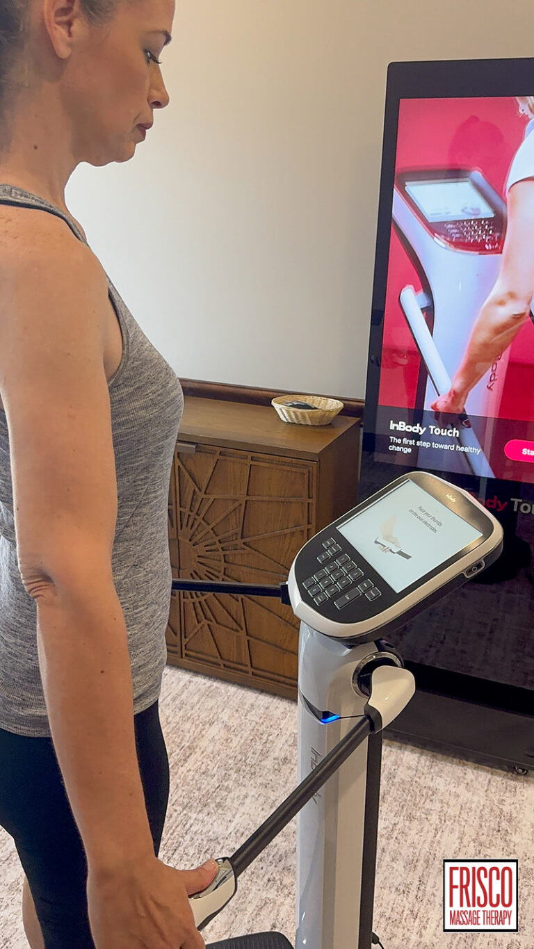 A woman standing on an InBody 580 body composition scale while holding the hand sensors.