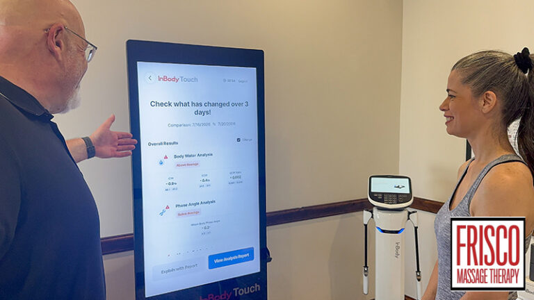 A man points to a body composition analysis screen while a woman looks on.